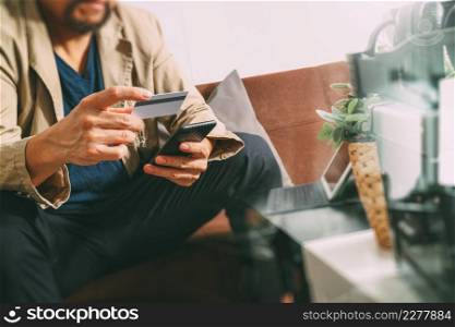 hipster hand using smart phone,digital tablet docking keyboard,holding cradit card payments online business,sitting on sofa in living room,work at home concept,filter effect