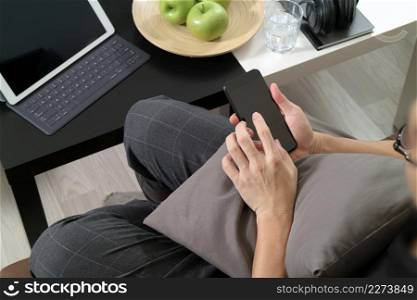 hipster hand using smart phone for mobile payments online business,glass of water,sitting on sofa in living room,green apples in wooden tray