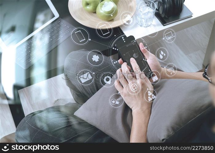 hipster hand using smart phone for mobile payments online business,headphone,sitting on sofa in living room,green apples in wooden tray,graphic interfce icons virtual screen
