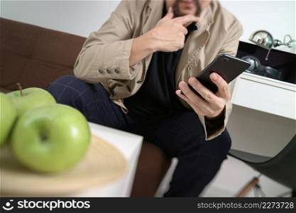 hipster hand using smart phone for mobile payments online business,sitting on sofa in living room,holding green apple in wooden tray