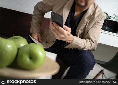 hipster hand using smart phone for mobile payments online business,sitting on sofa in living room,holding green apple in wooden tray