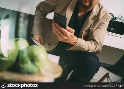 hipster hand using smart phone for mobile payments online business,sitting on sofa in living room,holding green apple in wooden tray,filter