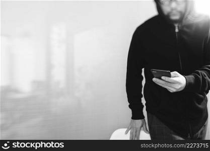 hipster male in a hood hand using mobile phone payments online shopping,omni channel,front view,black and white
