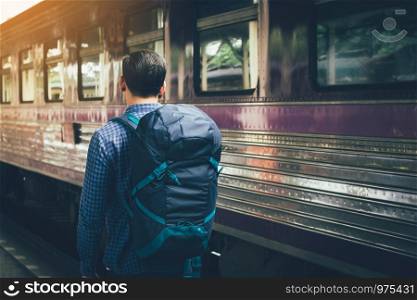 Hipster man standing at platform train station waiting and looking future concept.
