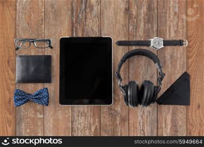 hipster personal stuff and objects concept - tablet pc computer, headphones, wallet, eyeglasses and wristwatch on wooden table background