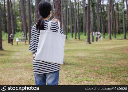 hipster woman holding white cotton bag at park