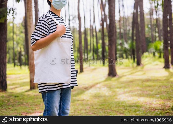 hipster woman holding white cotton bag at park