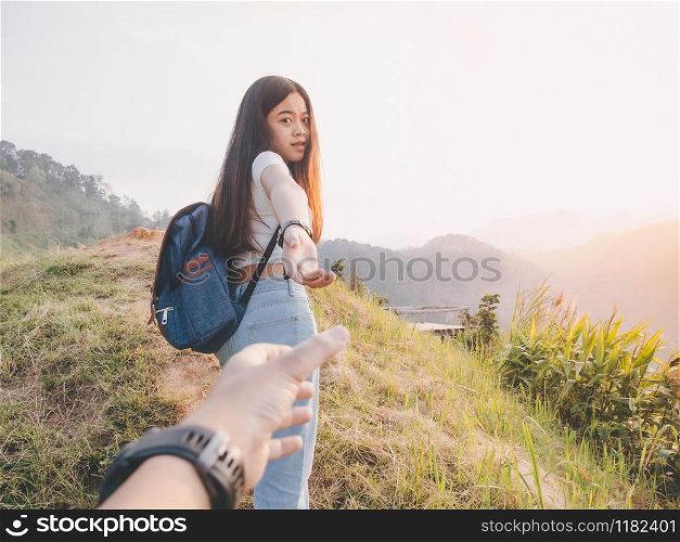 hipster woman traveler with backpack holding man?s hand and leading him on hill. Couple travel vacation concept