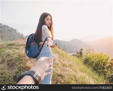 hipster woman traveler with backpack holding man?s hand and leading him on hill. Couple travel vacation concept
