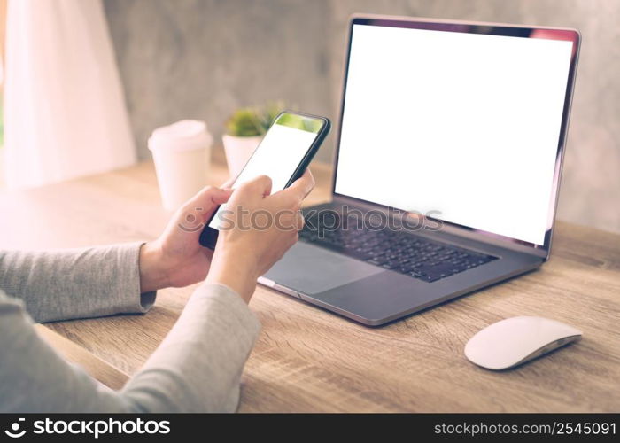 Hipster women holding phone and using laptop on wooden table in coffee shop.