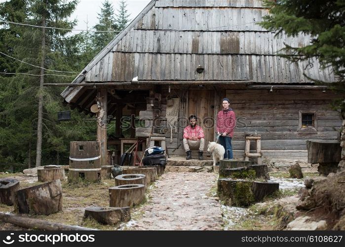 hipsters couple portrait, two young man with white husky dog sitting in front of old wooden retro house