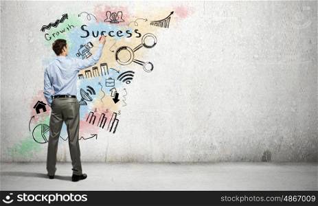His bright strategy plan . Back view of businessman drawing business sketches on wall