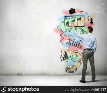 His bright strategy plan . Back view of businessman drawing business sketches on wall