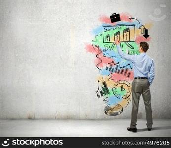 His bright strategy plan . Back view of businessman drawing business sketches on wall