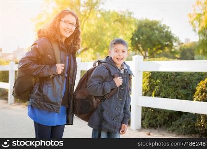 Hispanic Brother and Sister Wearing Backpacks Walking.