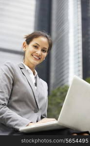 Hispanic Businesswoman Working On Laptop Outside Office
