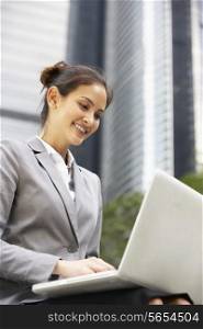 Hispanic Businesswoman Working On Laptop Outside Office