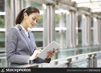 Hispanic Businesswoman Working On Tablet Computer Outside Office