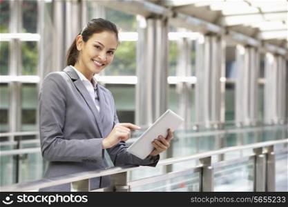 Hispanic Businesswoman Working On Tablet Computer Outside Office
