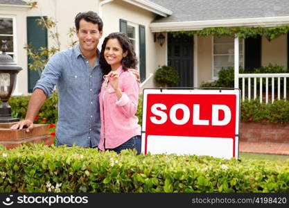 Hispanic couple outside home with sold sign