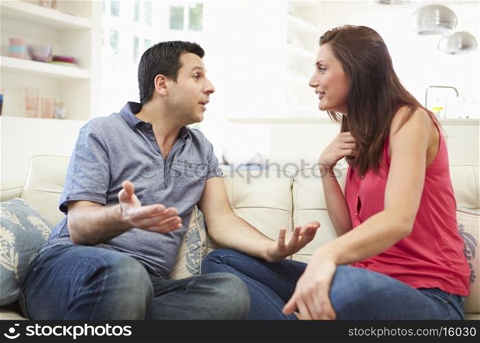 Hispanic Couple Sitting On Sofa Arguing