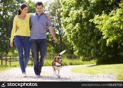 Hispanic Couple Taking Dog For Walk In Countryside
