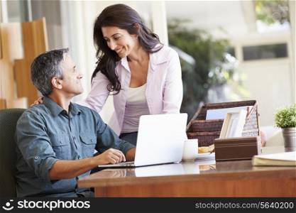 Hispanic Couple Using Laptop On Desk At Home