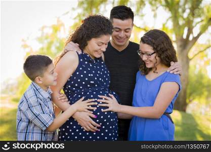 Hispanic Family Hands on Pregnant Mother Tummy Feeling Baby Kick Outdoors At The Park.
