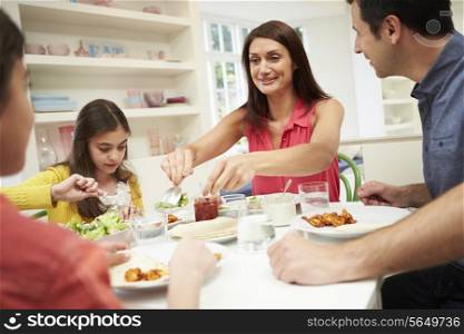 Hispanic Family Sitting At Table Eating Meal Together