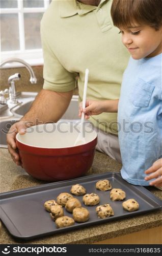 Hispanic father and son in kitchen making cookies.