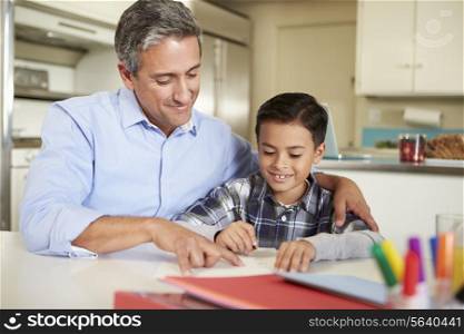 Hispanic Father Helping Son With Homework At Table