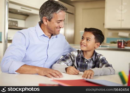 Hispanic Father Helping Son With Homework At Table