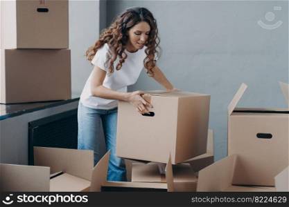 Hispanic female tenant gathering things to move out from rented apartment. Woman renter with cardboard boxes, packing personal belongings for relocation. Moving, rental dwelling concept.. Female tenant packing things in boxes to move out from rented apartment. Moving, rental dwelling