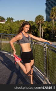 Hispanic girl in fitness clothing stretching before jogging