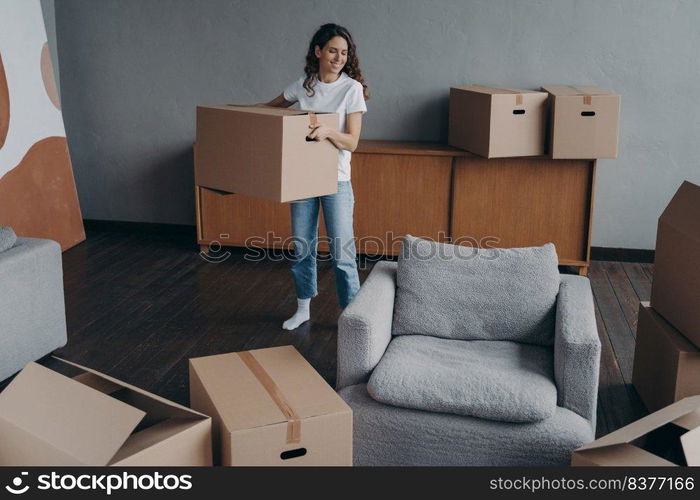 Hispanic girl is holding box and leaving apartment. Happy young woman relocates alone. Single lady moves. Real estate purchase, mortgage, delivery service ordering concept.. Hispanic girl is holding box and leaving apartment. Happy young woman relocates alone.