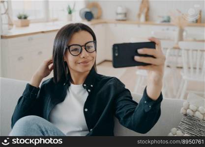 Hispanic girl is making selfie on smartphone. Woman is relaxing and using mobile phone camera. European lady enjoying time at home. Mobile phone, technologies and application using.. Hispanic girl is making selfie on smartphone. Woman is relaxing and using mobile phone camera.
