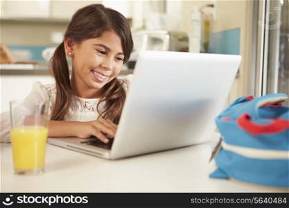Hispanic Girl Using Laptop To Do Homework At Table