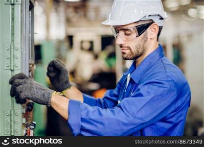 Hispanic latin labor worker hard working with safety glasses and helmet with heavy metal machine in factory industry .