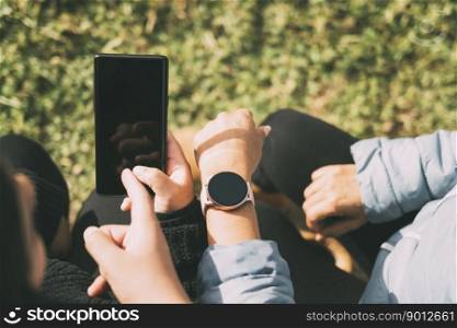 Hispanic male teenager holding smartphone looking away while sitting on grass with Hispanic mother and sister in park on sunny day,. Hispanic male teenager holding smartphone looking away while sitting on grass with Hispanic mother and sister in park on sunny day