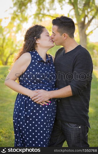 Hispanic Man Kisses His Pregnant Wife and Feels Their Baby Kick Outdoors At the Park.