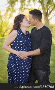 Hispanic Man Kisses His Pregnant Wife and Feels Their Baby Kick Outdoors At the Park.