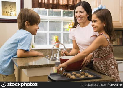 Hispanic mother and children in kitchen making cookies.