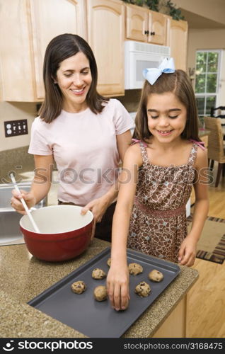 Hispanic mother and daughter in kitchen making cookies.