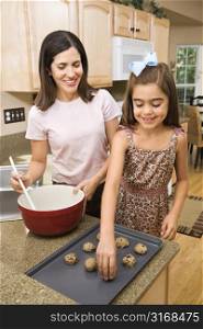 Hispanic mother and daughter in kitchen making cookies.