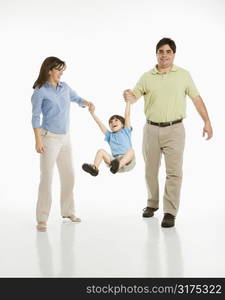 Hispanic mother and father swinging son against white background.