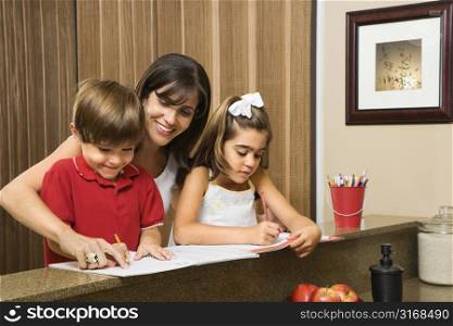 Hispanic mother helping children with homework.