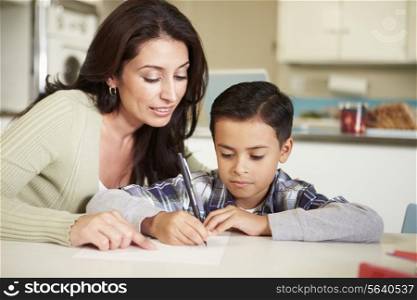 Hispanic Mother Helping Son With Homework At Table
