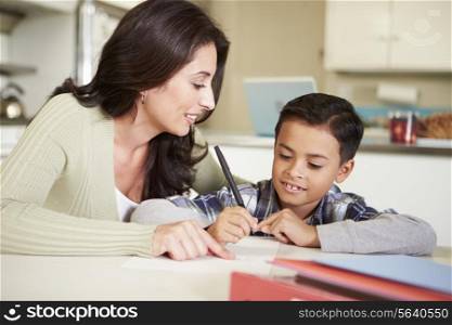 Hispanic Mother Helping Son With Homework At Table