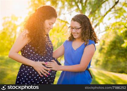 Hispanic Pregnant Mother and Daughter Feeling Belly.