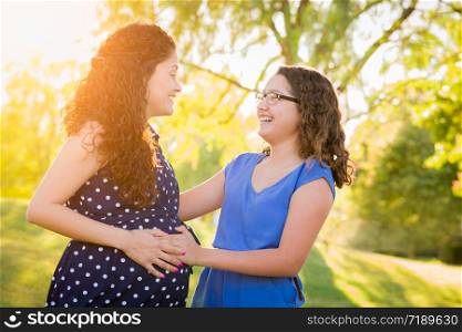 Hispanic Pregnant Mother With Young Daughter Outdoors.